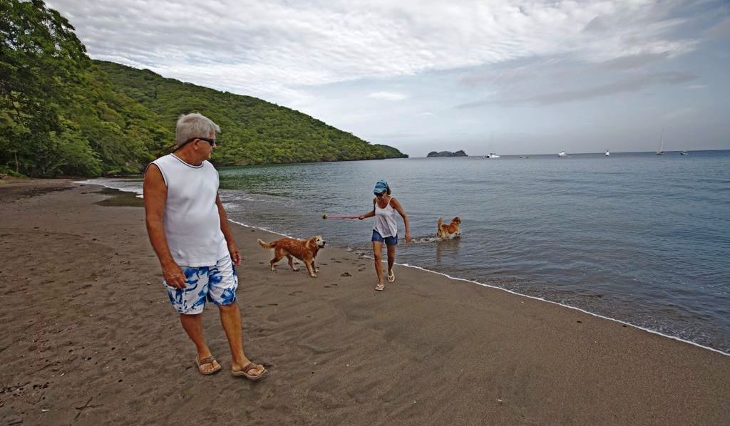 Couple walking on the beach with their dogs in Playa Hermosa
